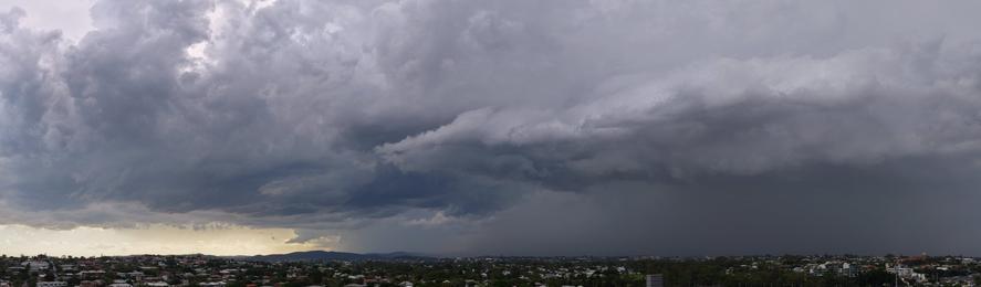 An aerial panorama of the suburban brisbane skyline, taken by drone, showing a dark storm rolling in