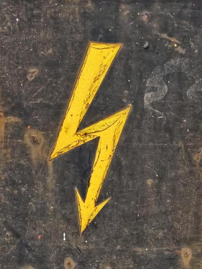 Warnzeichen: Auf schwarzem Hintergrund aufgemalter, gelber Blitz.
