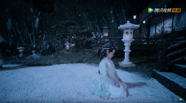 Young Lan Wangji kneels at night on snowy ground before dark, snow-dusted steps. A line of spaced out stone lanterns glowing with dim light lead away and out of frame. Lan Wangji's head tilts downward, chin tucked, and his eyes are closed. His open hands rest on his thighs, palms down.