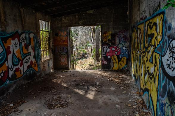 A room in an abandoned mill complex with graffiti on the walls.