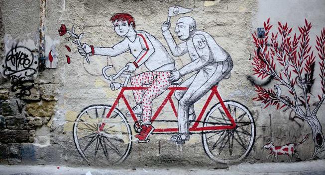 Graffiti in Palermo, Sizilien: Zwei Menschen auf einem Tandem. Der vordere hält eine Rose in der Hand, der hintere eine Fahne mit dem CND-Friedenssymbol.