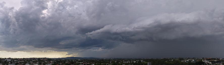 An aerial panorama of the suburban brisbane skyline, taken by drone, showing a dark storm rolling in
