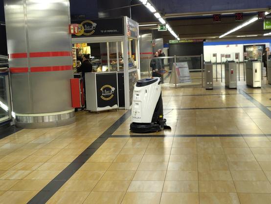 Estación de metro. Se ve un robot limpiador al fondo fregando.