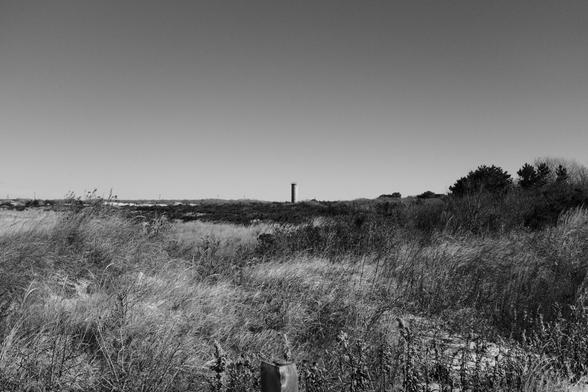 Monochrome image. Near the set, in the distance a concrete cylindrical tower rises from the brush.