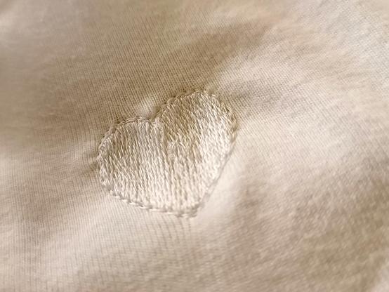 Une forme de cœur, brodée de fil blanc sur un tissu blanc. C'est discret et ça permet de raccommoder un petit trou.