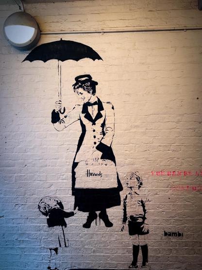 A cartoon Mary Poppins with two children, a girl and a boy, painted on white brick. Part of the caption in red can be seen on the right hand side.