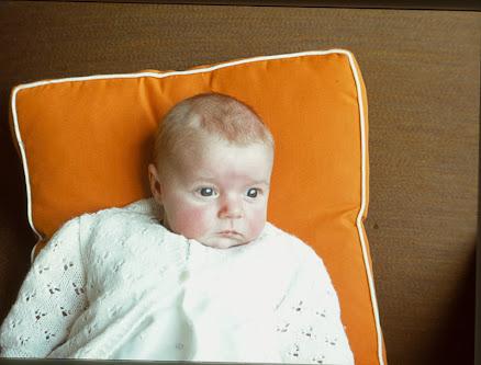 A 35mm slide photograph of A small child on an orange cushion