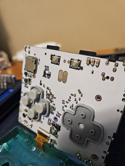 The motherboard of an anbernic R G 3 5 X X S P with two conductive surfaces near the middle, the one on the left has signs of corrosion