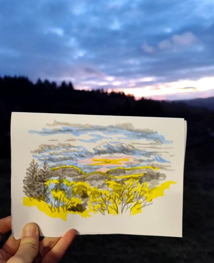 Croquis aux feutres d'un coucher de soleilsur la ligne des collines, photographié devant le ciel en question