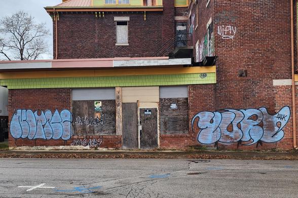large abandoned red brick business and residence. among other smaller graffiti are what appear to be the words "NOTICE" and "YUP,Y" in bug blue puffy letters.