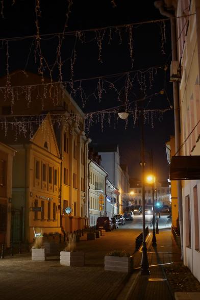 Vulica Revaliucyjnaja in Minsk, Belarus, on a November night in 2025, with active street lights and a car approaching in the distance from plošča Svabody