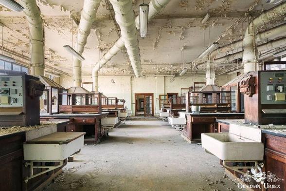 The photo shows an old lab filled with wooden furniture, sinks, and scientific equipment,