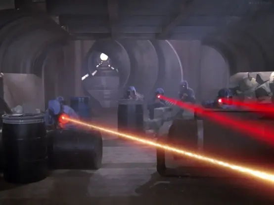 In Too Short a Season, an early episode of Star Trek: The Next Generation, we see several ponchoed soldiers ducking behind barrels in a dusty tunnel. They are firing red phaser beams to the camera's right, and we see Starfleet phaser beams return fire. In the background, inexplicably, is Mega Maid's ear canal from Spaceballs.