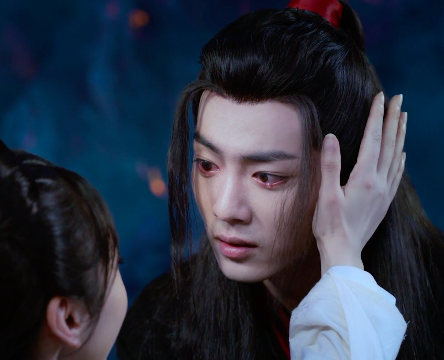 At Nightless City, Wei Wuxian kneels in front of Jiang Yanli, his eyes red-rimmed and full of tears, while she reaches up with her right hand to cradle the side of his head.