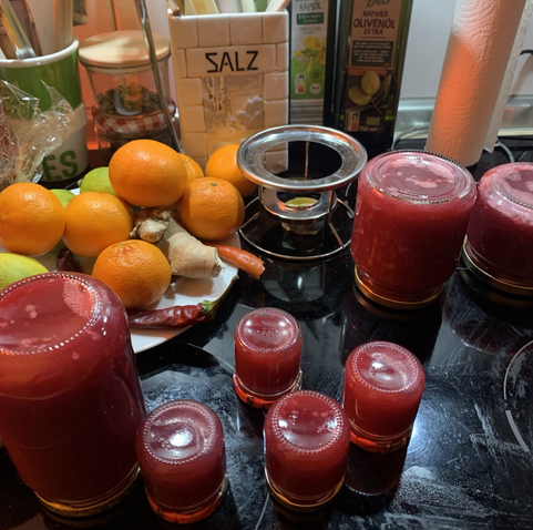 Fertiges Fruchtmus rötlich aus Äpfeln. Die Glaser stehen noch umgedreht nach dem Abfüllen in der Küche.Links liegen Mandarinen, Zitronen und Ingwer, Fotos vom 21.11.25.Definitiv