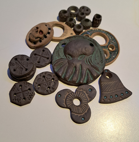 Clay pendants, pearls and buttons laying on a table like a pile of old treasure.