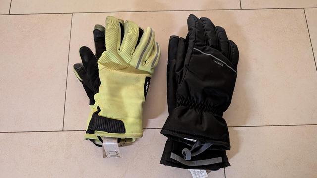 Photo of two pairs of thick gloves on the floor. The left pair is bright yellow, the right pair is black.
