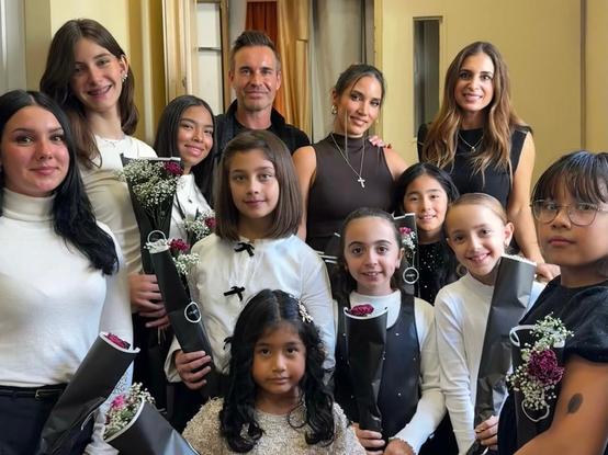 En primer plano nueve niñas que integran el coro y detrás el productor David Santisteban, la artista India Martínez y la vocal de la asociación Olvidados Nereida Coig.