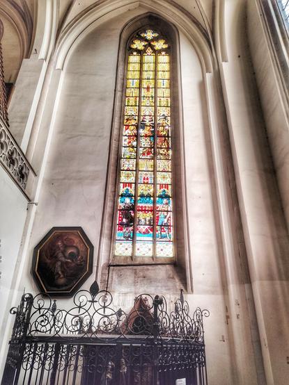 Hohes, schmales Spitzbogenfenster aus buntem Glas in der Kirche St. Nikolaus in Cheb, Tschechien.