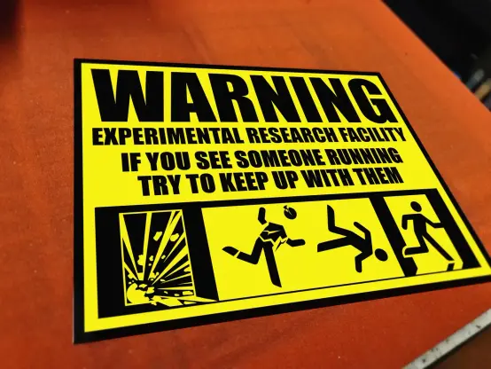 A metal sign saying "Warning experimental research facility. If you see someone running, try to keep up.