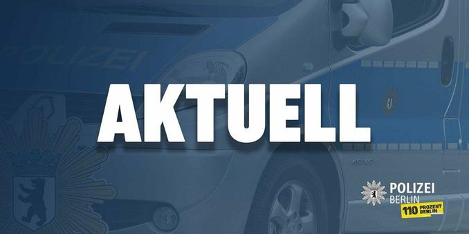 Nahaufnahme eines Berliner Polizeifahrzeugs. Im Vordergrund prangt der Text "AKUELL" in großen, fetten, weißen Buchstaben. Unterhalb des Textes befinden sich das Berliner Polizeilogo und der Slogan "110 Prozent Berlin". Das Fahrzeug ist blau und weiß lackiert, typisch für Polizeifahrzeuge. Der Vorderteil des Wagens mit Scheinwerfer und Reifen ist zu sehen. Im Hintergrund ist das Wort "POLIZEI" undeutlich abgebildet.