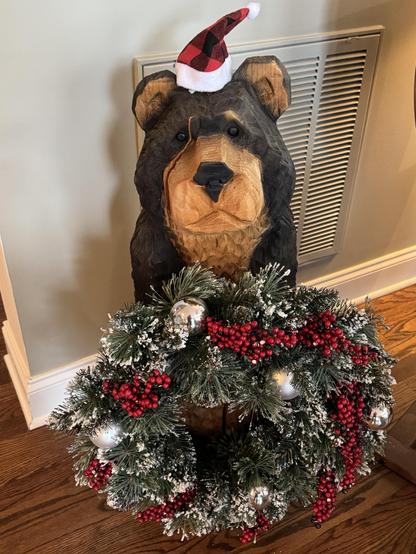 My main-level carved bear, Branch, has had to cede his regular spot to a fir tree for the season, but to make up for it has put away his usual welcome sign for a wreath and a small Santa hat.  He's not 100% pleased with the hat.