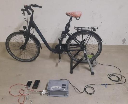 Fahrrad in Rollentrainer, an den ein Motor angebracht ist, um damit Strom zu erzeugen.