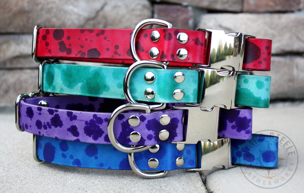 4 leather puppy collars stacked, each a solid color with splatters in a darker shade, and with silver colored hardware. Top to bottom: red, teal, purple, blue