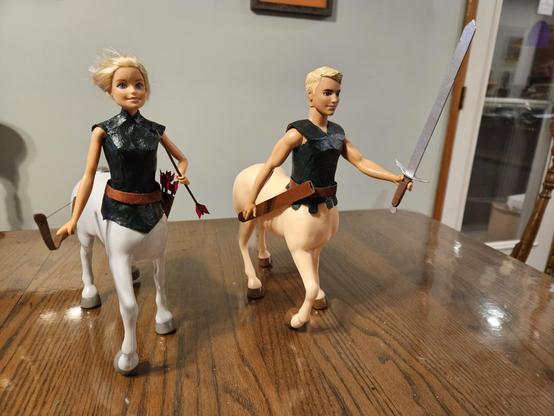 Ken and Barbie dolls, sans legs, merged with plastic horse bodies, sans heads using a heat gun and super glue gel.  Ken is fitted out with a broadsword, belt, and scabbard;  Barbie is fitted out with a belt, quiver of arrows, and a bow.  Both have forest-green tunics on their torso.