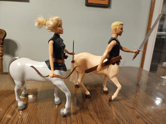 Ken and Barbie dolls, sans legs, merged with plastic horse bodies, sans heads using a heat gun and super glue gel.  Ken is fitted out with a broadsword, belt, and scabbard;  Barbie is fitted out with a belt, quiver of arrows, and a bow.  Both have forest-green tunics on their torso.