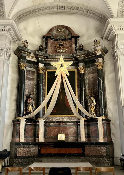 Ein grosser beleuchteter Stern mit Schweif schmückt den Chorraum der Kirche. (Bei Tageslicht.)