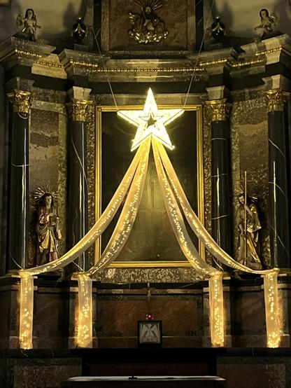 Ein grosser beleuchteter Stern mit Schweif schmückt den Chorraum der Kirche. (Bei Dämmerlicht.)