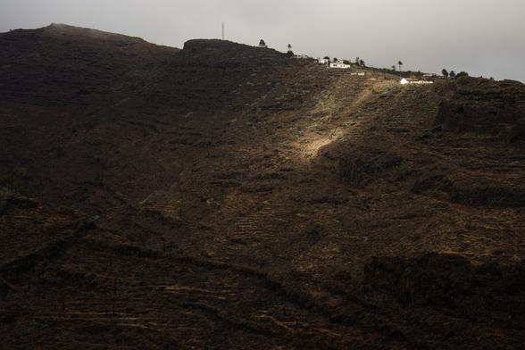Un raggio di sole illumina il fianco di un canyon spoglio.