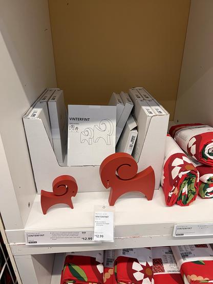 Photo of two red wooden goats with curled horns. One goat is larger than the other. They are in front of a box labeled “vinterfint.”