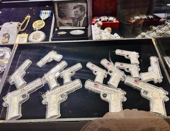 Bullion grade silver miniature g^ns, some with US flags, all in custom plastic cases. Some jewelry and a medal are seen.