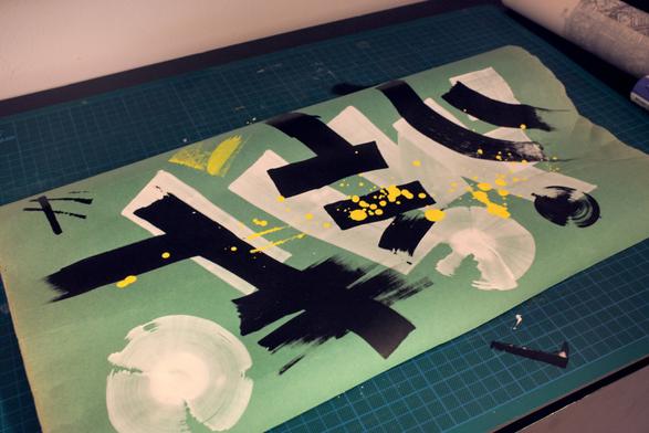 Abstract art: a green piece of paper with thick white lines, smaller black strokes and yellow splotches.