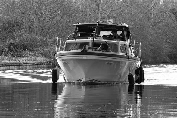 Monochrome photo for a motorboat crusing down the canal.