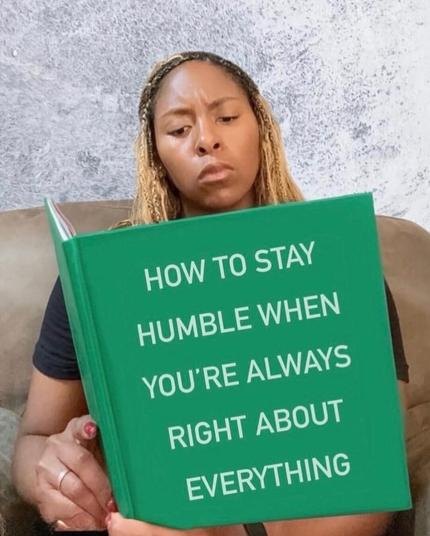 A woman reads a green book titled “How to Stay Humble When You’re Always Right About Everything” with a deeply serious expression, as if she’s searching for tips on surviving her own brilliance.