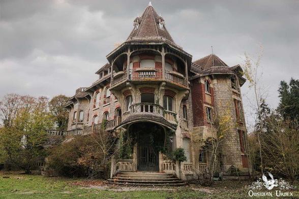 An abandoned 19th-century mansion in northern France, with a round tower, overgrown vegetation, and weathered brick and stone exterior beneath a cloudy sky.