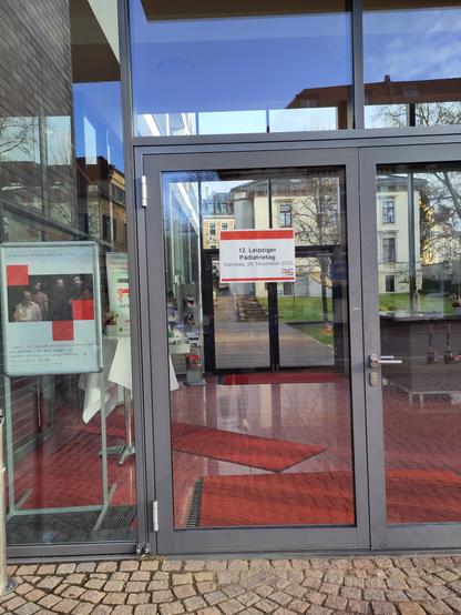 Gläserne Eingangstür mit Schild für die Veranstaltung