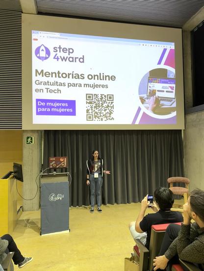 Mia Salazar en l'escenari de l'auditori de l'a11yConf 2025 a Girona parlant de step 4ward mentoria online per dones en Tech davant de la audiència