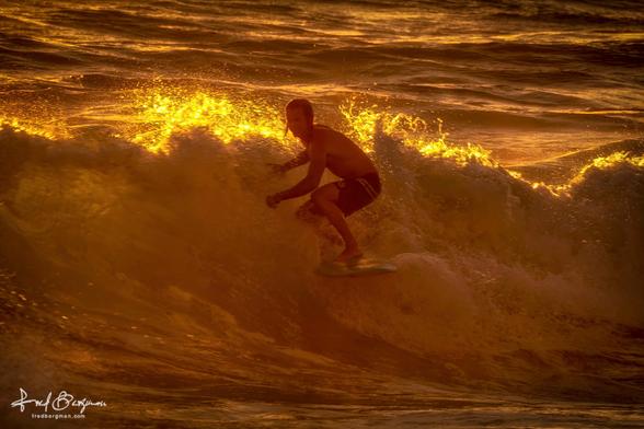 Surfer riding a wave against a sun drenched backdrop