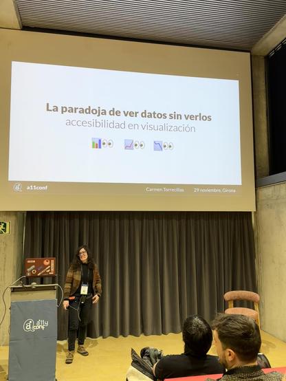 Carmen Torrecillas en l'escenari de l'auditori de l'a11yConf 2025 a Girona parlant de visualitzacio de dades accessible davant de la audiència