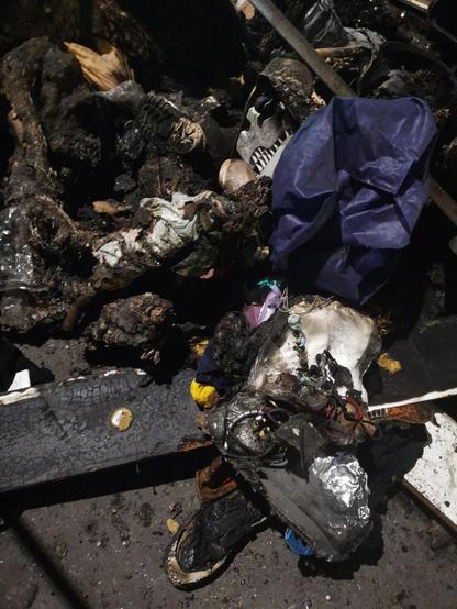Some burnt belongings on an asphalt floor.