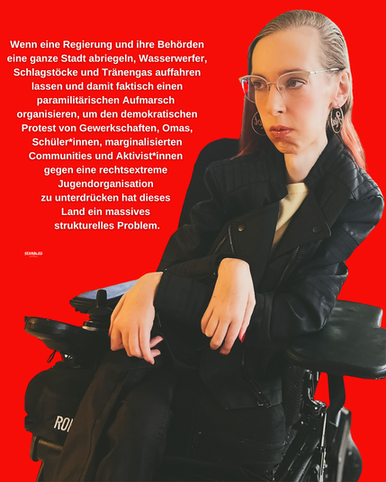 Vor einem kräftig roten Hintergrund sitze ich und trage eine schwarze Lederjacke, eine hellbeige Bluse und eine silberne Brille. Mein Blick geht ernst und konzentriert nach rechts aus dem Bild heraus. Die Hände liegen locker im Schoß, eine davon stützt leicht auf die Armlehne des Rollstuhls. Links neben mir steht ein längerer weißer Text im Blocksatz: "Wenn eine Regierung und ihre Behörden eine ganze Stadt abriegeln, Wasserwerfer, Schlagstöcke und Tränengas auffahren lassen und damit faktisch einen paramilitärischen Aufmarsch organisieren, um den demokratischen Protest von Gewerkschaften, Omas, Schüler*innen, marginalisierten Communities und Aktivist*innen gegen eine rechtsextreme 
Jugendorganisation zu unterdrücken hat dieses Land ein massives 
strukturelles Problem."
