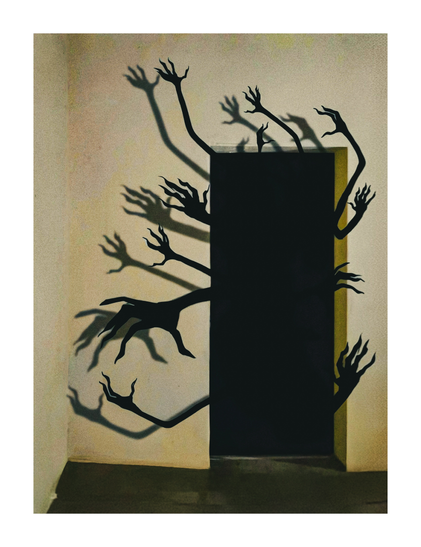 A Photograph of a dark doorway with numerous branching, claw-like arms emerging from it. The background is a plain, beige wall with subtle shadows cast by the arms. The floor is dark greeny brown which contrasts with the light wall.