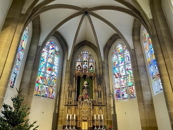 Altar dahinter bunte Kirchenfenster