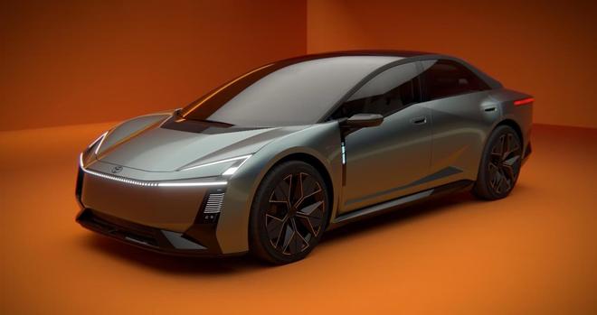 A sleek, futuristic electric sedan featuring a smooth body design and distinctive black wheels. The car is set against a bright orange background, highlighting its modern aesthetic.