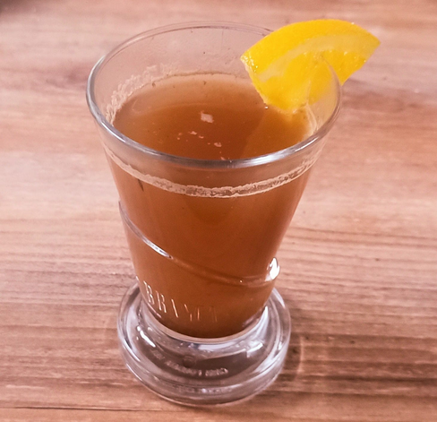 In einem Glas der hellbraune Glühwein, dekoriert mit einem Stückchen Orange