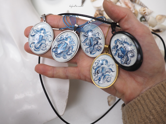 Halte verschiedene ovale Anhänger mit handgemaltem Motiv Krakenlady in der Hand, Größe je ca. 30x40mm